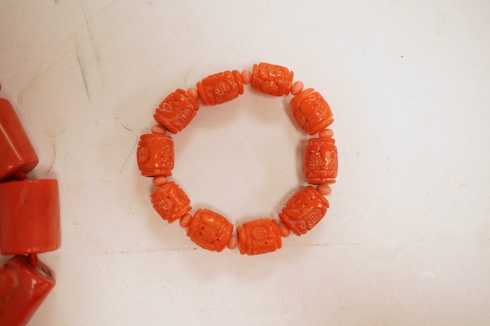 Two coral bead necklaces, one composed of large cylindrical coral beads, approximately 2.5-3.5cm each, total length 49cm; and a bracelet composed of carved coral beads spaced by smaller pink coral beads, on an elasticate